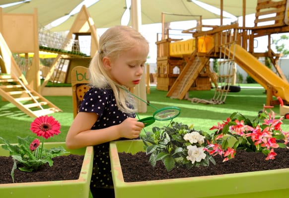 A little girl is looking at plants in a garden.