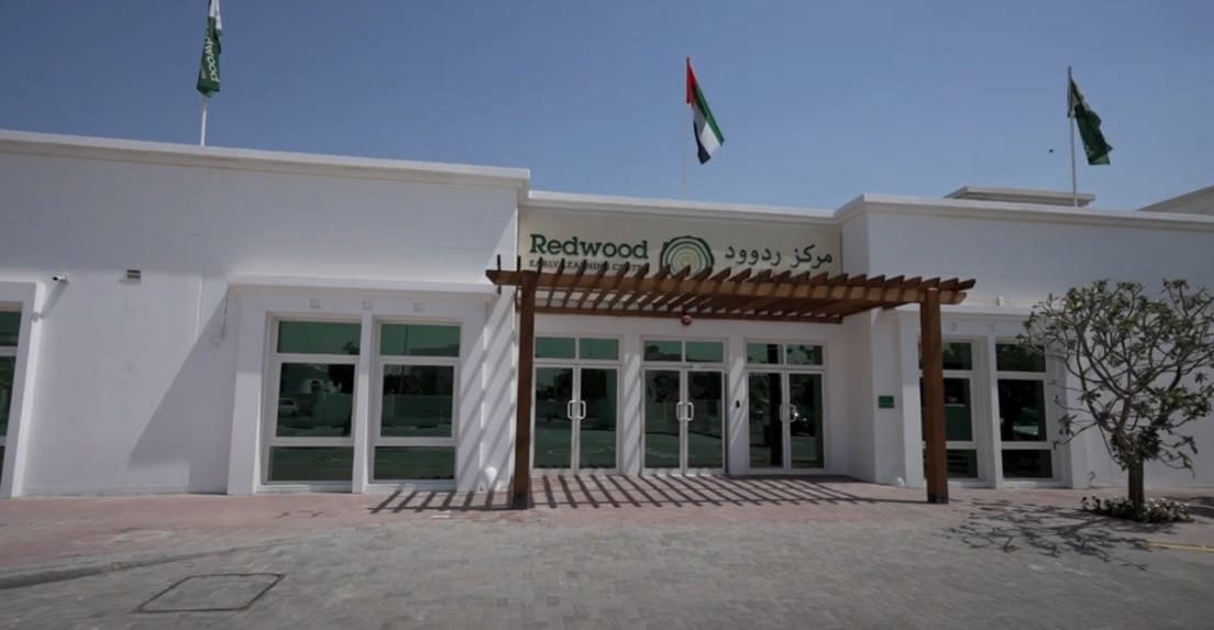 A white building with flags outside.